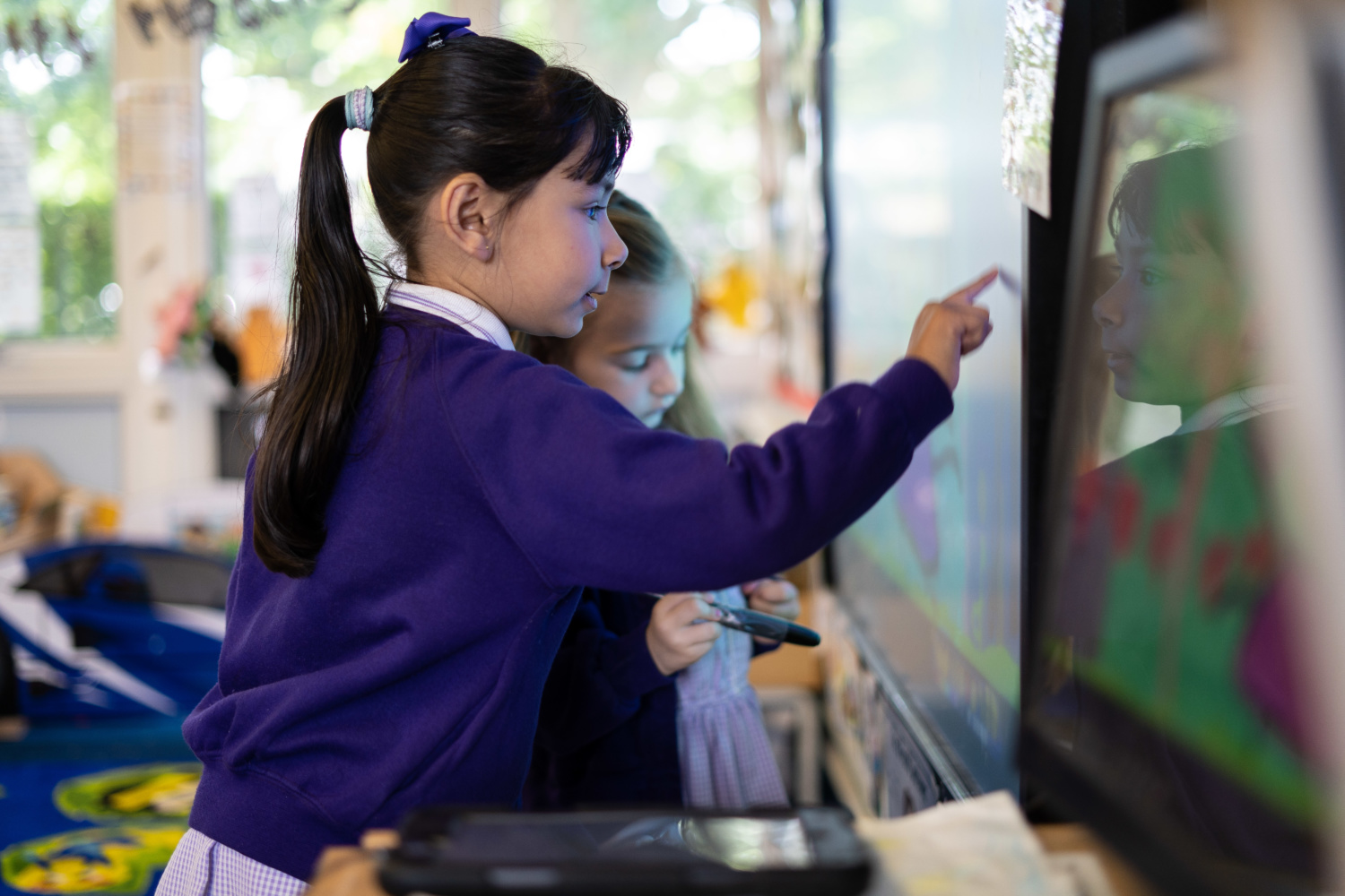 Two pupils are pictured interacting with a SMART Interactive Board at the front of a classroom.
