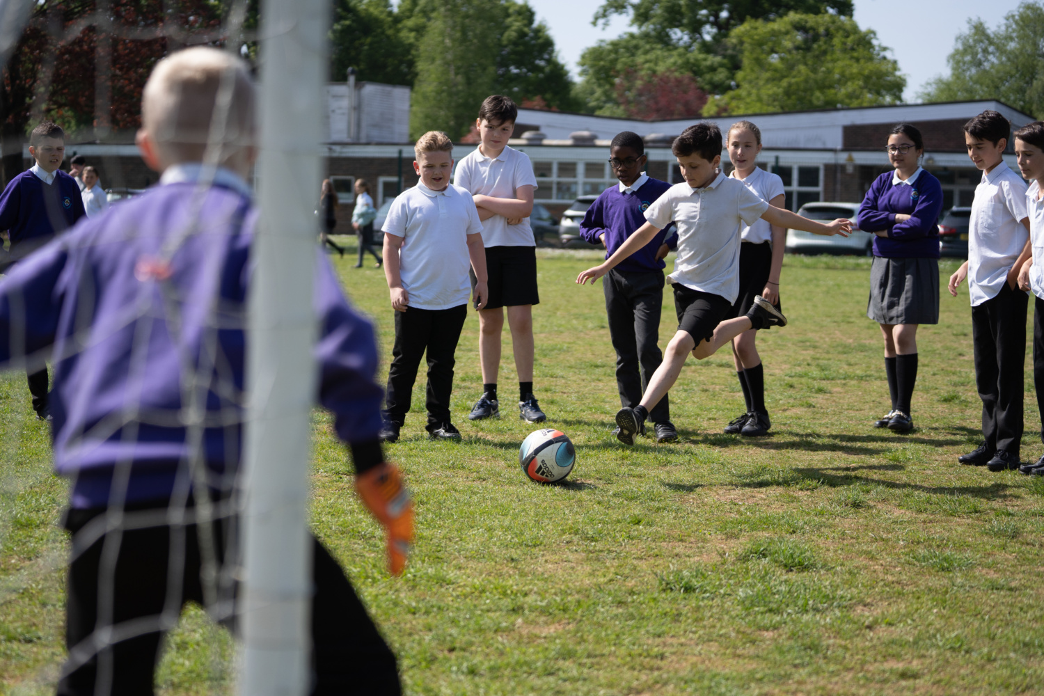 A group of Tree Tops pupils are seen playing a game of Football with one another. A boy is pictured about to take a shot. In the foreground the goalie can be seen about to block the ball.