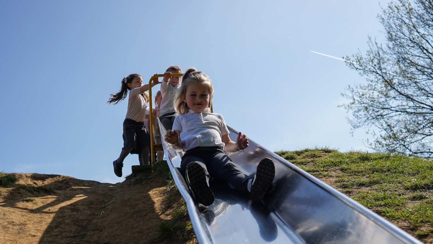 A small group of female pupils are seen queuing up to go down a slide on the academy grounds.